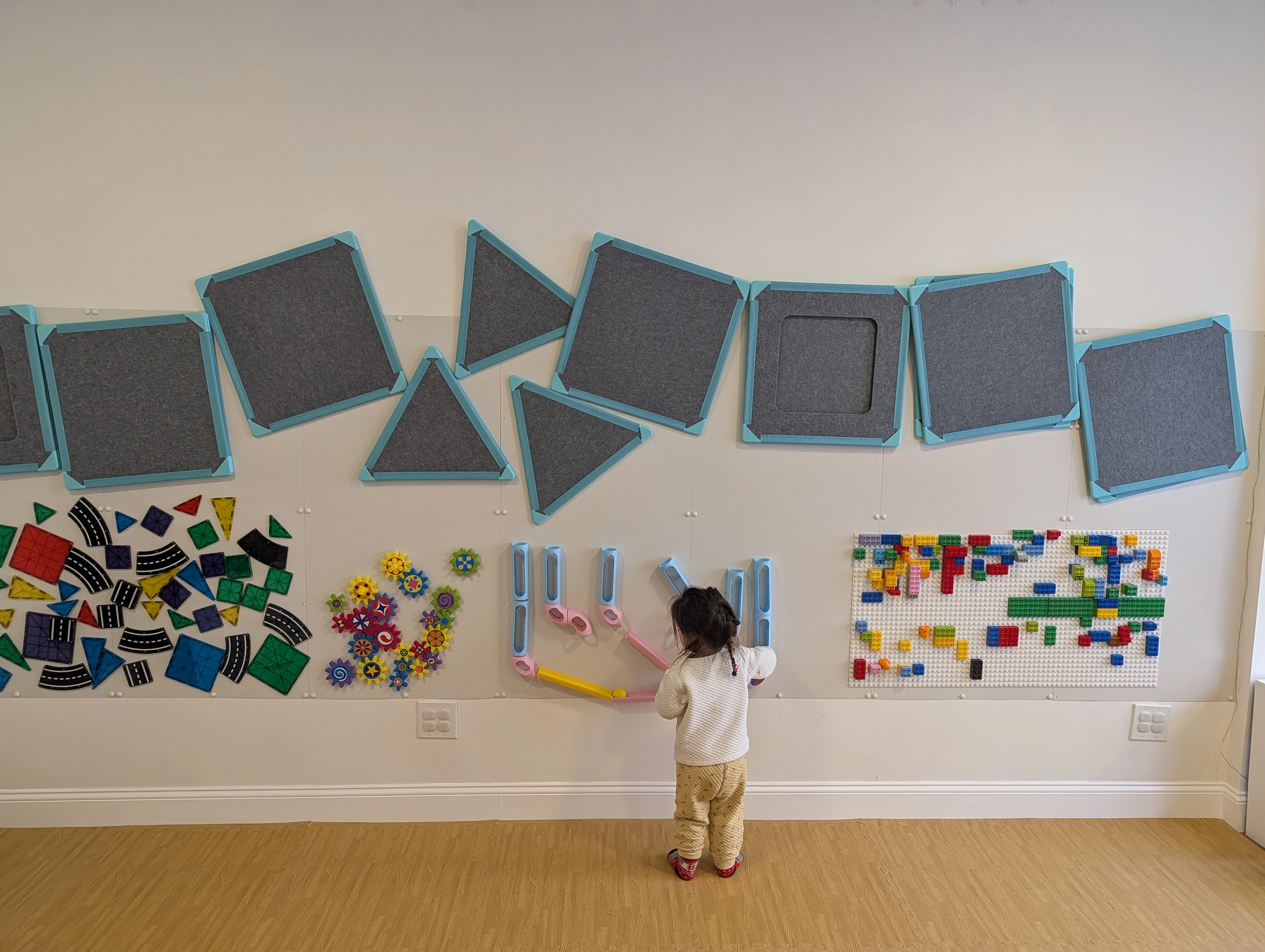 A child happily drawing on the wall at Cortelyou Music & Play